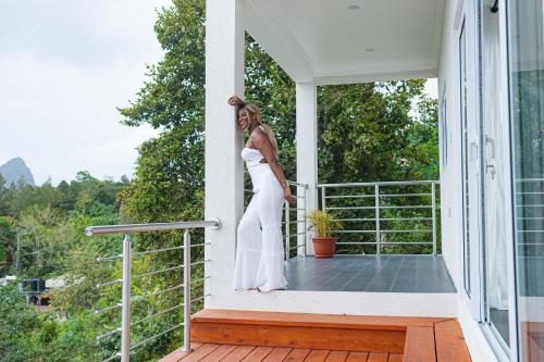 a woman in a white dress standing on a porch at Majestic Dream Villas in Choiseul