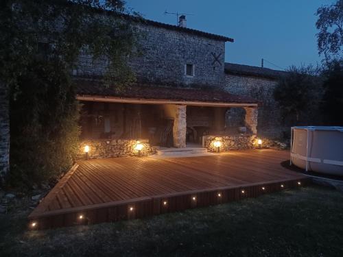 a wooden deck with lights in front of a building at Le Quereau in Saint-Macoux
