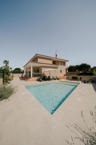 a villa with a swimming pool in front of a house at Villa Victoria Paradise in Cala en Blanes