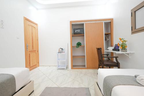a white room with two beds and a chair at Résidence America in Dakhla