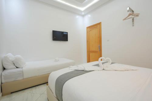 a bedroom with two beds and a tv on a wall at Résidence America in Dakhla