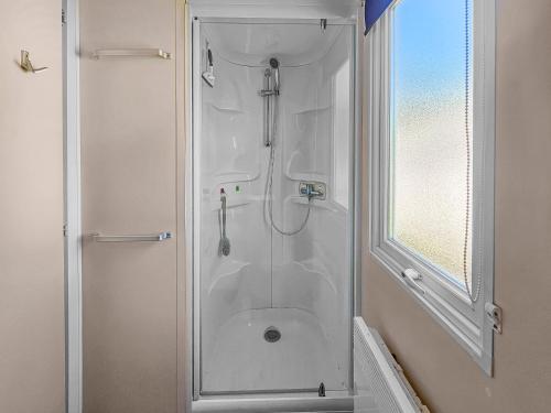 une douche avec une porte vitrée dans une salle de bain dans l'établissement Cerisya, terrasse semi couverte, à Litteau