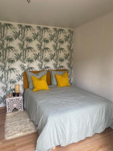 a bedroom with a large bed with yellow pillows at Chambre calme in Tremblay En France
