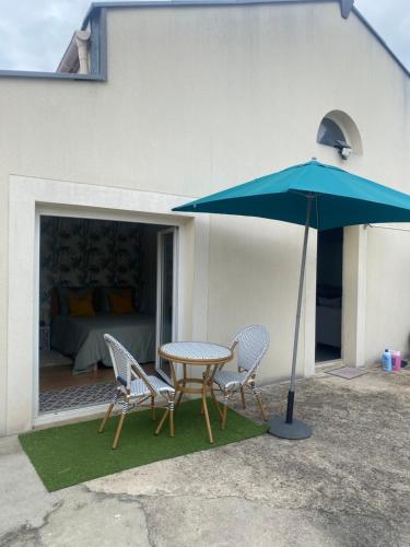 une table et des chaises avec un parapluie bleu dans l'établissement Chambre calme, à Tremblay-en-France