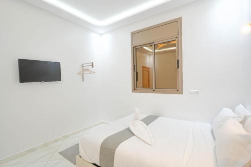 a white bedroom with a bed and a window at Résidence America in Dakhla
