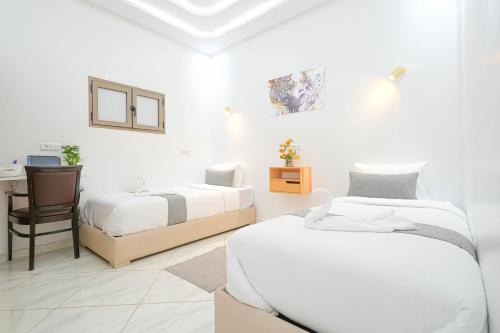 a white bedroom with two beds and a desk at Résidence America in Dakhla