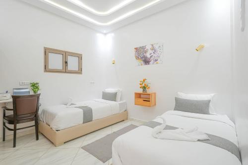Cette chambre blanche comprend deux lits et un bureau. dans l'établissement Résidence America, à Dakhla