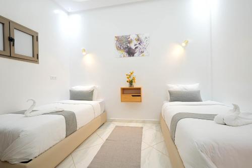 two beds in a room with white walls at Résidence America in Dakhla