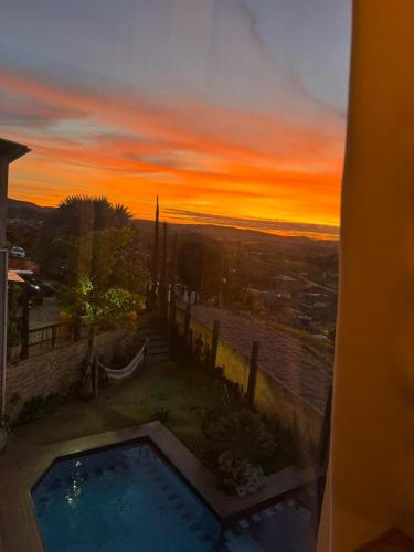 a sunset over a swimming pool in a house at Pousada Recanto Querubins in Paty do Alferes