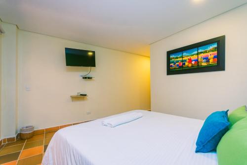 a bedroom with a white bed with a tv on the wall at Hotel Bambu Guatape in Guatapé