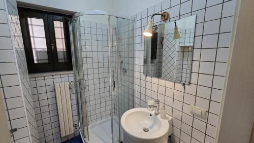 a white tiled bathroom with a sink and a shower at La Città Vecchia house Salerno centro in Salerno