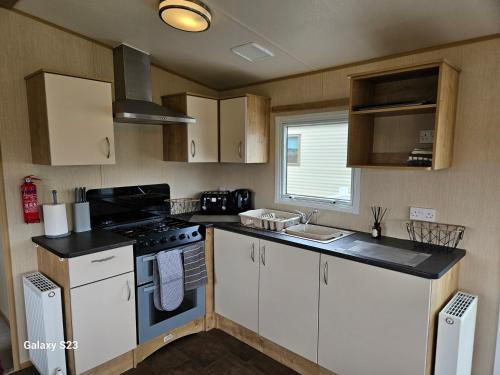 a kitchen with white cabinets and a stove top oven at Thurston Manor Caravan Park, Pony Meadow in Dunbar