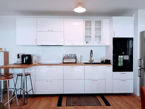 une cuisine avec des armoires blanches et un réfrigérateur noir dans l'établissement Saint jean gare bel T3 appartement free parking, à Bordeaux