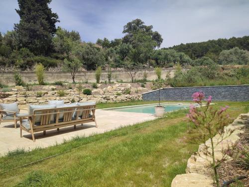 un jardin avec un banc et une piscine dans l'établissement Les jardins de Vacqueyras, à Vacqueyras