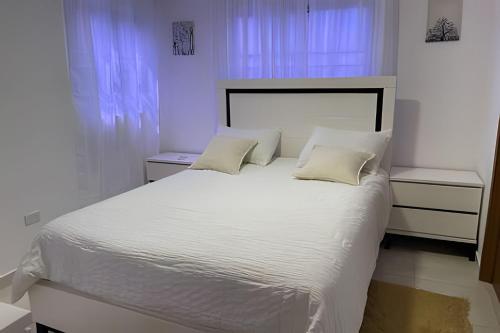 a bedroom with a white bed with white sheets and pillows at Sunshine Palmares de Caleta in La Romana