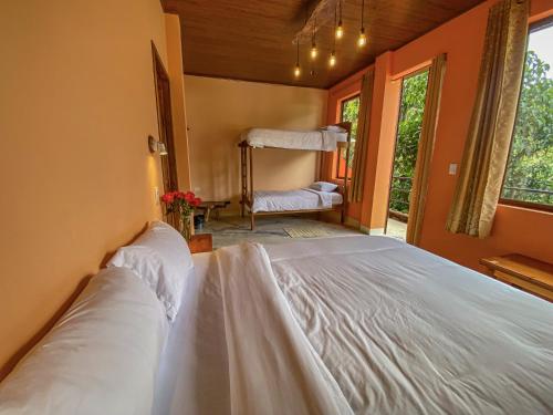 a bedroom with a large white bed in a room at Cabañas Armonía y Jardín de Orquídeas in Mindo