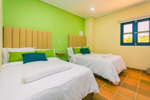 two beds in a room with green walls at Hotel Bambu Guatape in Guatapé