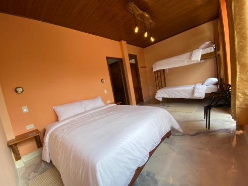 a bedroom with a large white bed and two bunk beds at Cabañas Armonía y Jardín de Orquídeas in Mindo