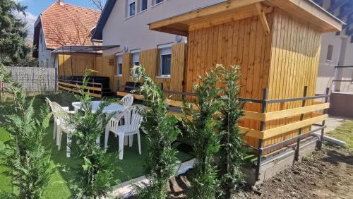 a wooden shed with a table and chairs in a yard at Rigófészek Apartmanház in Gárdony