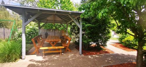 a wooden table and bench under a pavilion at Rigófészek Apartmanház in Gárdony