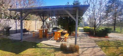 a gazebo with two benches and a table at Rigófészek Apartmanház in Gárdony