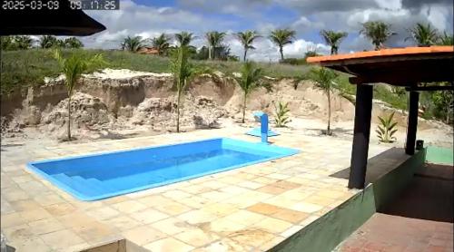 a swimming pool in front of a beach with palm trees at Casa Pitombeira in Aracati