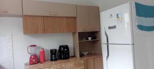 a kitchen with a white refrigerator and wooden cabinets at Casa ideal 5 quatros sendo 3 suítes 2 km do centro in Bananeiras