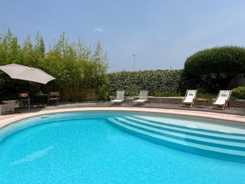 une grande piscine avec des chaises et un parasol dans l'établissement Grand studio vue sur la piscine, à Montferrier-sur-Lez