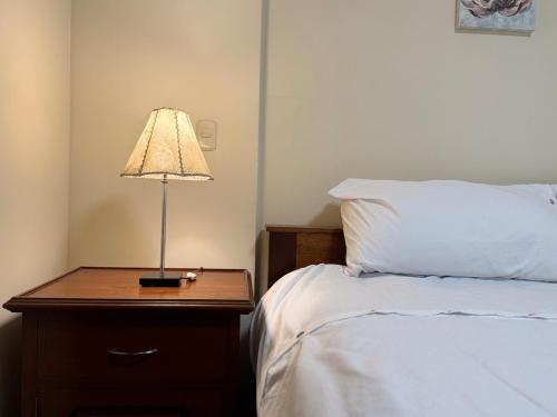 a lamp on a night stand next to a bed at Style and location in Miraflores by AG in Lima