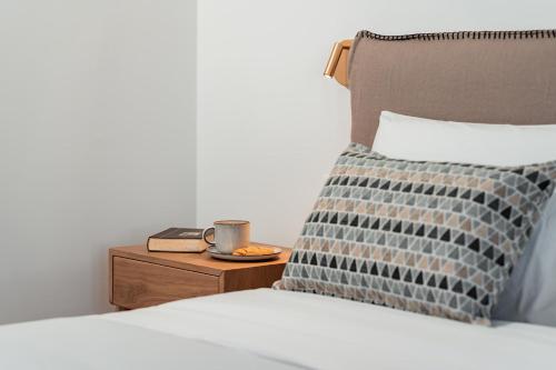 a bed with a pillow and a cup on a night stand at Platies Luxury Apartments Santorini in Éxo Goniá
