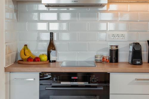 a kitchen with a counter with fruit and a bottle of wine at Platies Luxury Apartments Santorini in Éxo Goniá