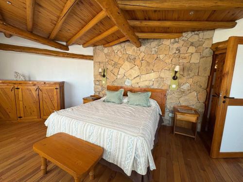 a bedroom with a bed and a stone wall at Lodge Copahue Expeditions in Caviahue
