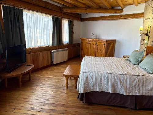 a bedroom with a bed and a flat screen tv at Lodge Copahue Expeditions in Caviahue