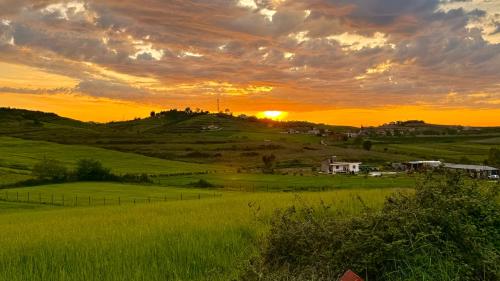 a sunset over a green field with the sun setting at Sunset Hill Villa in Durrës
