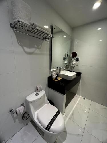 a white bathroom with a toilet and a sink at Hotel Dali Plaza Ejecutivo in Guadalajara