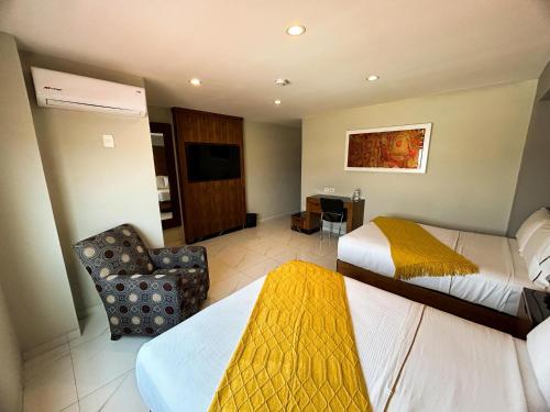 a hotel room with two beds and a chair at Hotel Dali Plaza Ejecutivo in Guadalajara