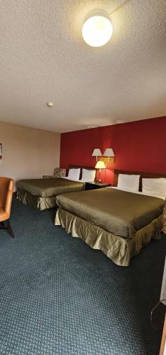 two beds in a hotel room with a red wall at Colonial Inn in Dyersville