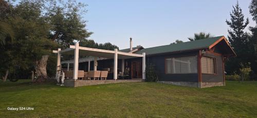 a house with a porch and chairs in a yard at Casa Lago Rapel in Las Cabras