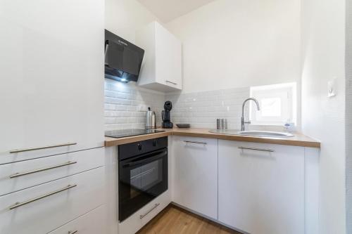 une cuisine blanche avec des armoires blanches et un évier dans l'établissement Le Sweet Plaisancier - Parking and Wi-Fi Gratuits-, à Mulhouse