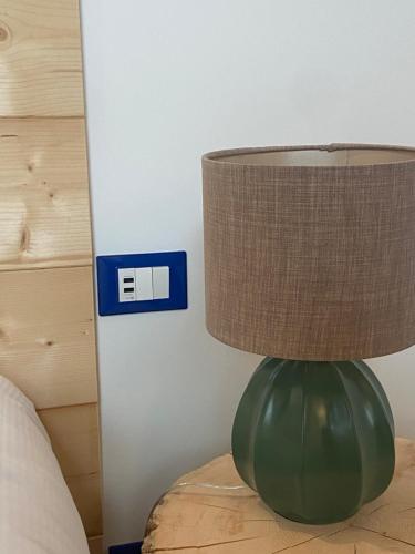 a green lamp sitting on a table next to a bed at Lussari Style Apartments in Camporosso in Valcanale