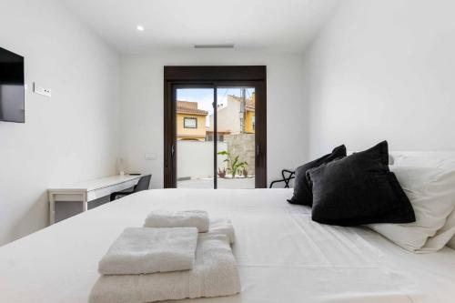 ein weißes Schlafzimmer mit einem großen weißen Bett mit schwarzen Kissen in der Unterkunft Sunny luxury corner house with private pool in San Pedro del Pinatar