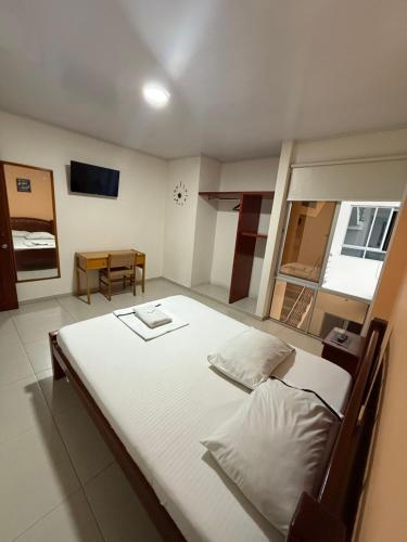 a bedroom with a large white bed and a table at HOTEL VILLAREAL VILLAVICENCiO in Villavicencio