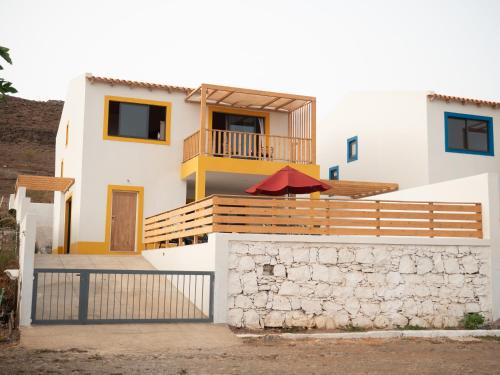 a house with a balcony with a red umbrella at Blue Coast Villas - Villa 6 in Cidade Velha