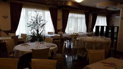 une salle à manger avec des tables blanches, des chaises et des fenêtres dans l'établissement Hotel Iscla, à Edolo