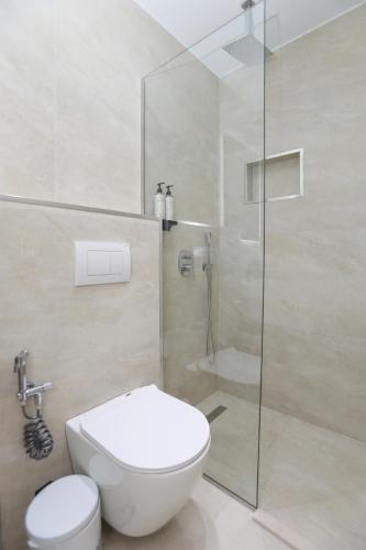 a bathroom with a toilet and a glass shower at Divos Apartments in Vlorë