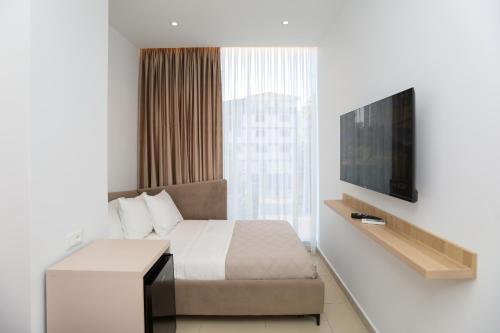 a bedroom with a bed and a flat screen tv at Divos Apartments in Vlorë