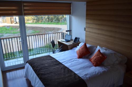 a bedroom with a bed and a balcony with a laptop at Ruta Hotel Alto La Cruz in Los Ángeles