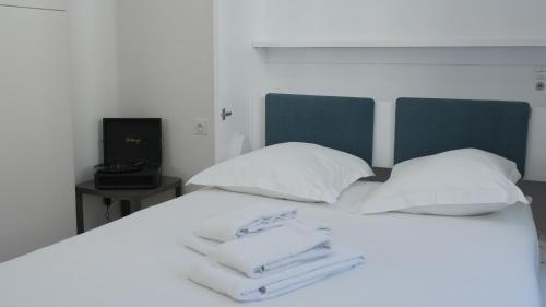 a bed with white sheets and pillows and a television at Maison Jacob - Hyper centre - Maison historique - Air conditioning - Wifi in Avignon