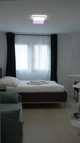 a bedroom with a bed with a window and a couch at Maison Jacob - Hyper centre - Maison historique - Air conditioning - Wifi in Avignon
