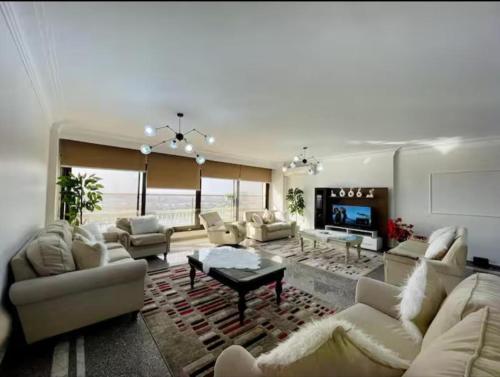 a large living room with white furniture and a television at Family apartment at The Nile maadi in Cairo